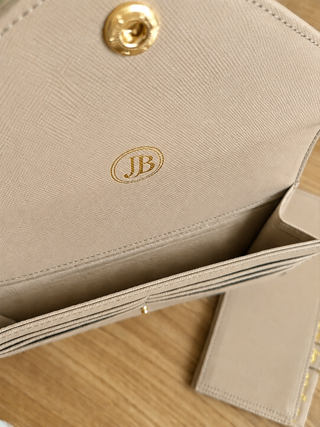 Close-up detail of the beige wallet organizer texture and gold logo
