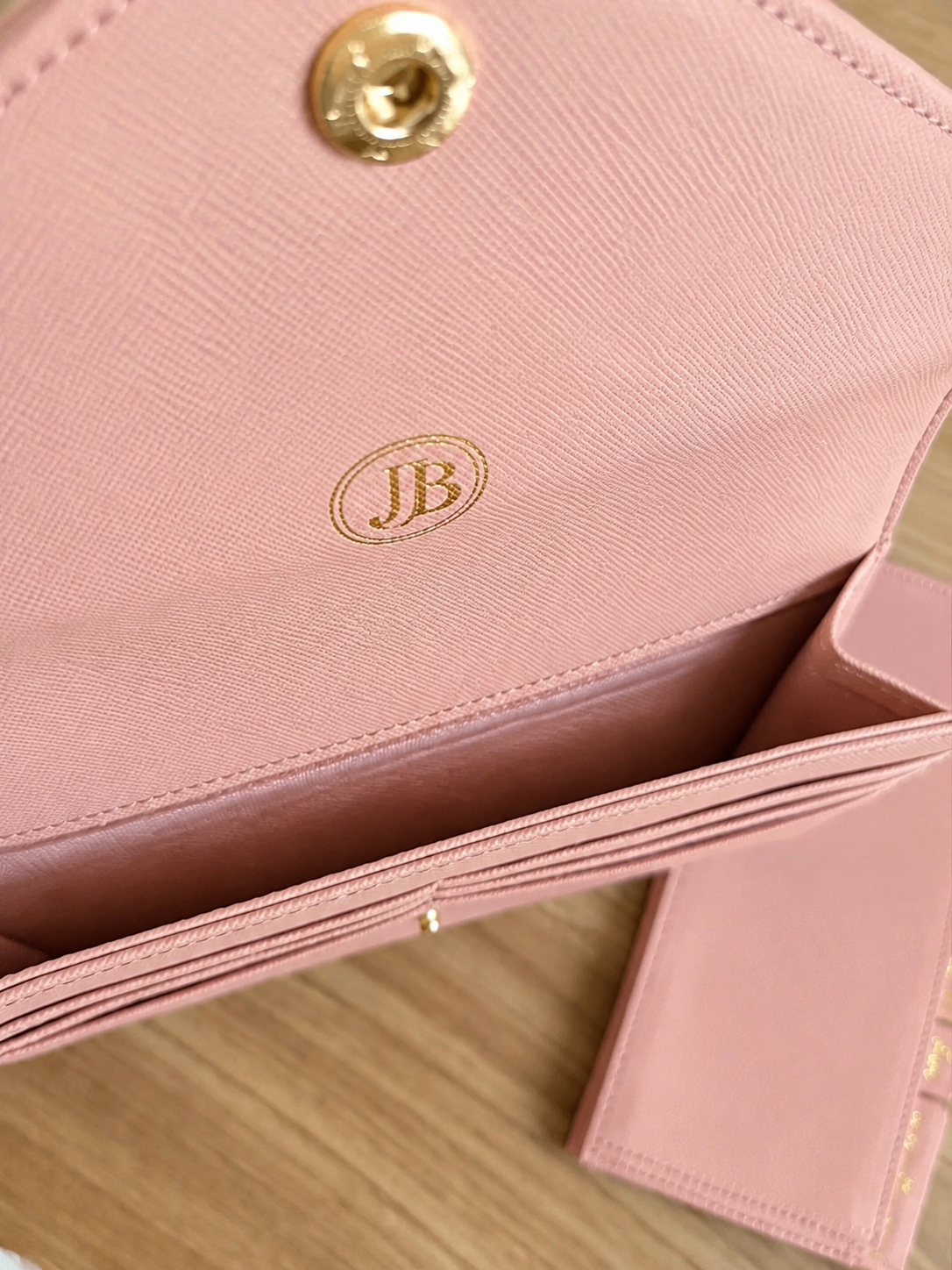 Close-up detail of the pink wallet organizer texture and gold logo
